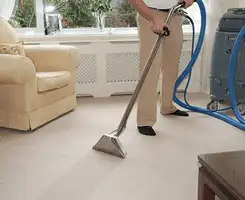 Carpet cleaning professional removing dirt and stains with a hot-water extraction tool in a home, Bloomington, IN.